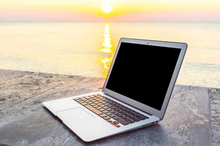 Laptop on a desk near the sunset, representing the best budget laptops for 2026 for work and college.